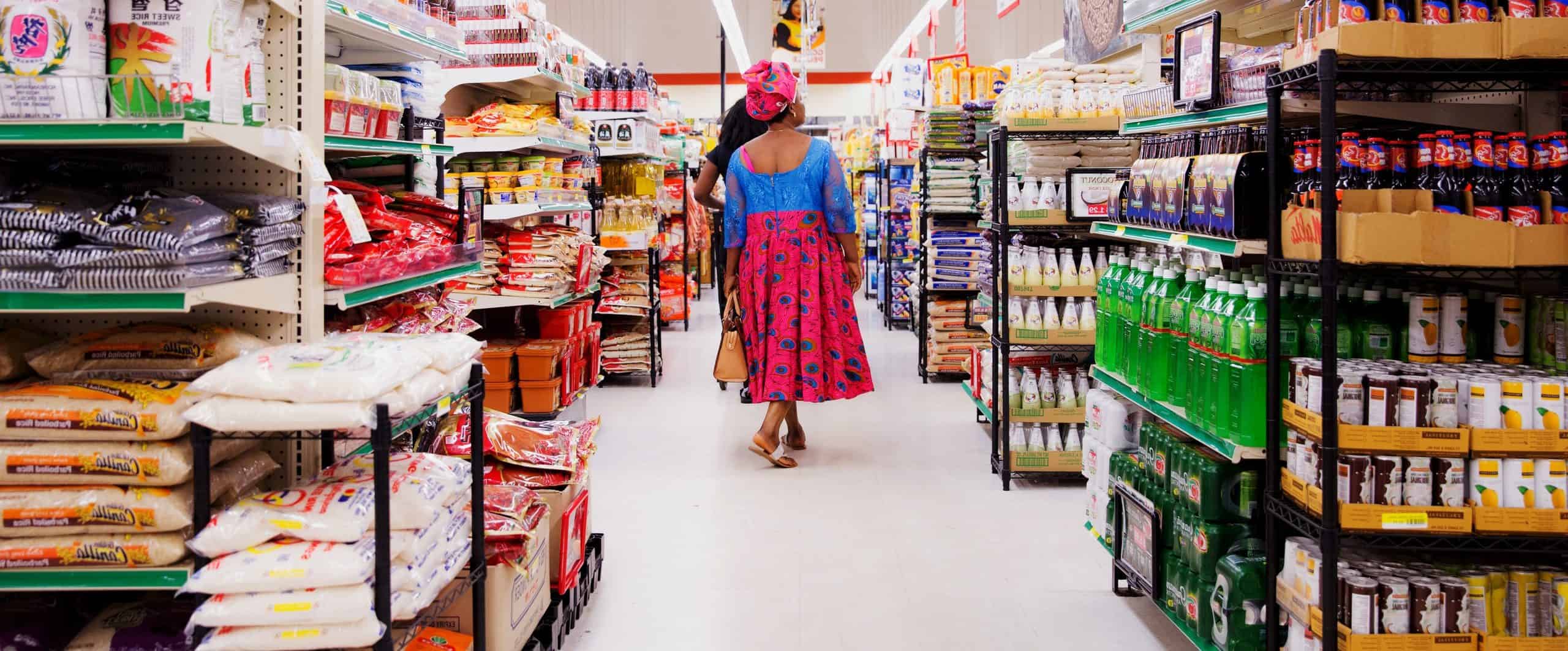 A woman walking down the aisle of a grocery store