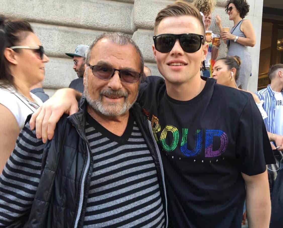 Two people posing for a photo during Pride week in a t-shirt that says "Proud"